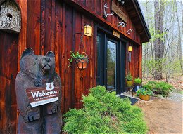 Exterior view of lodge with carved bear holding welcome sign